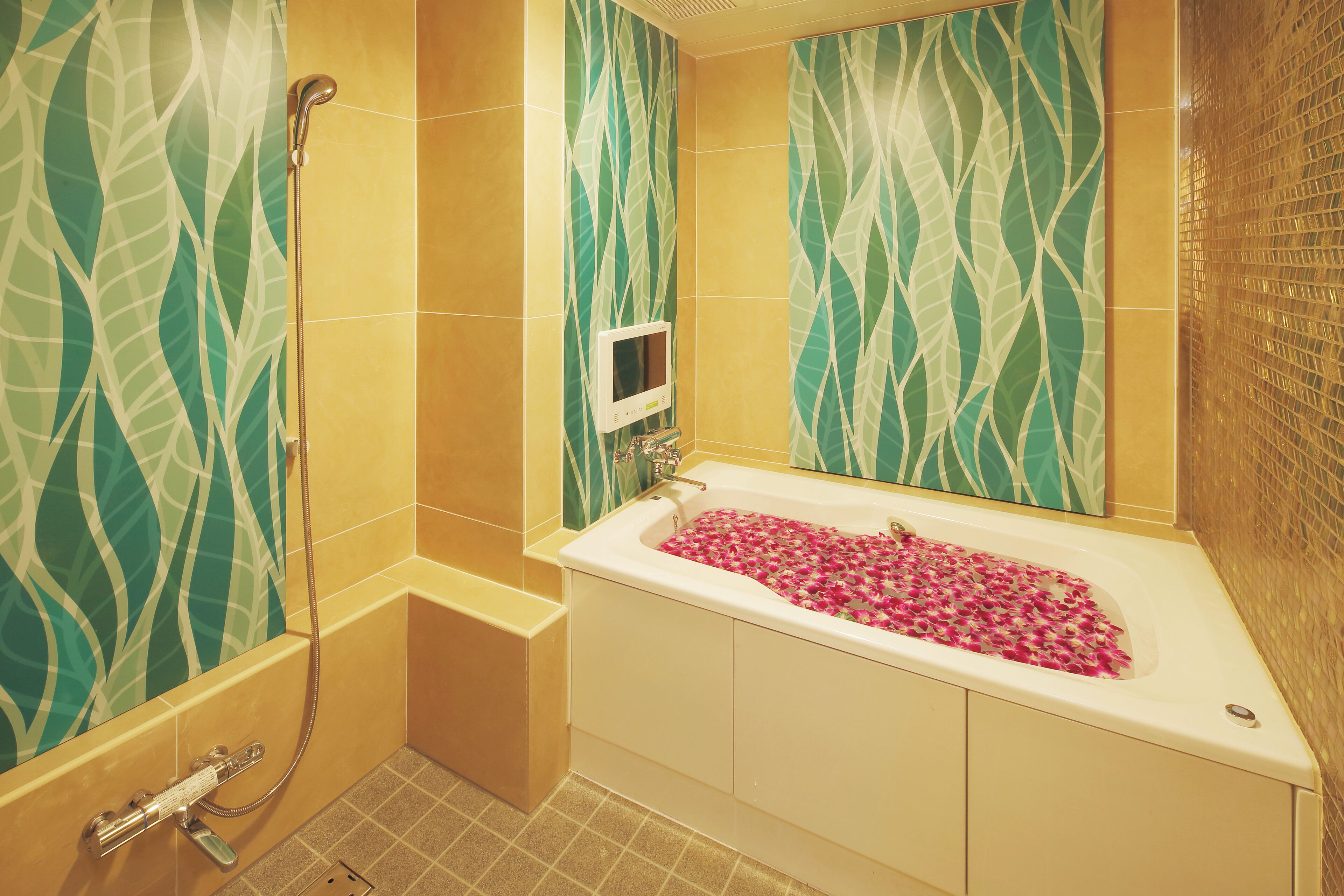 A bathroom with a bathtub filled with rose petals, a shower, and a wall-mounted control panel.