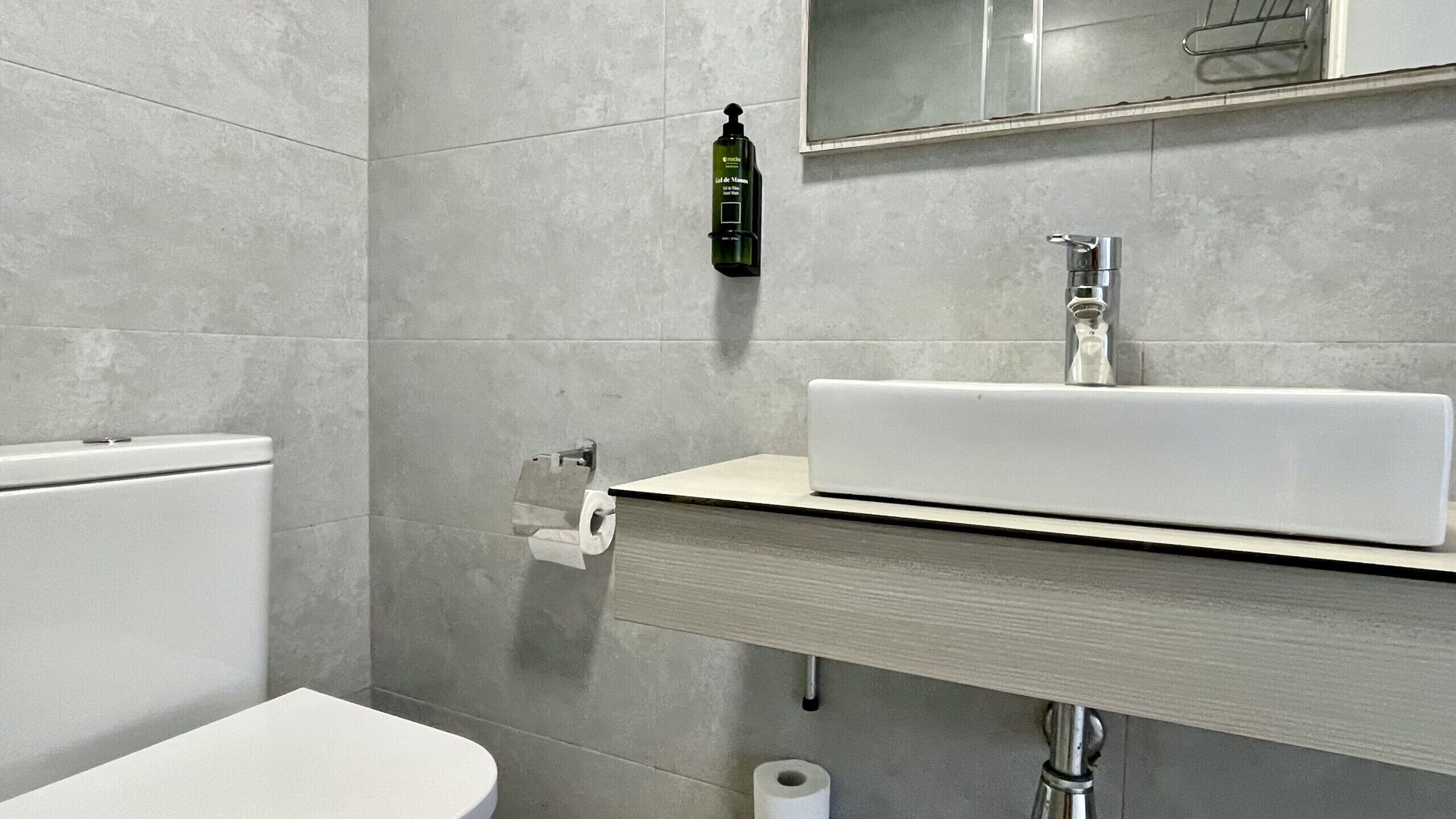 A modern bathroom with a toilet, sink, and toilet paper.