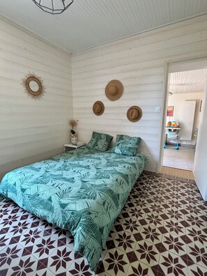 A bedroom with a bed, a wall-mounted mirror, and three hats. - Charming Renovated House with Garden, Terrace, Barbecue - 15 Min from the Beaches (Unknown)