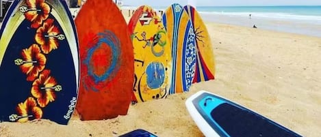 A row of colorful surfboards on a sandy beach.