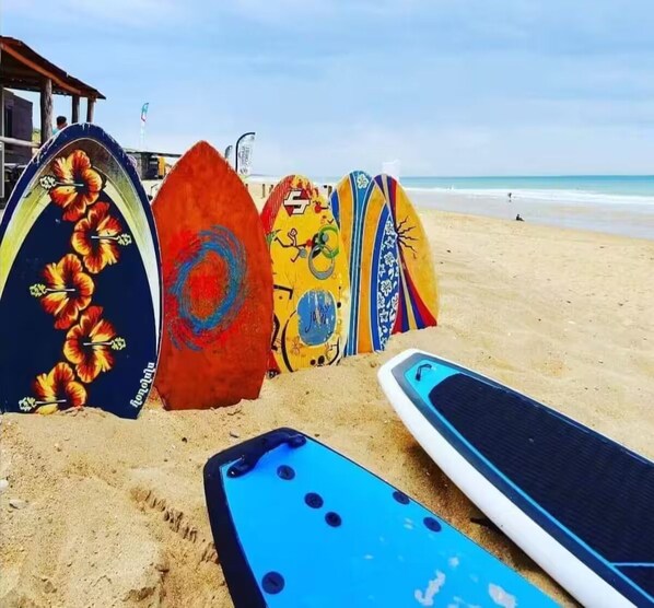A row of colorful surfboards on a sandy beach. - Charming Renovated House with Garden, Terrace, Barbecue - 15 Min from the Beaches (Unknown)