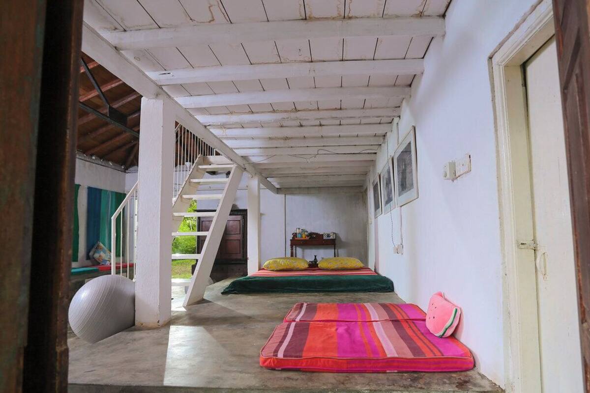 Un couloir avec un escalier menant à une pièce où se trouvent un lit et une petite table.