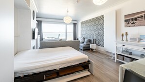 Ein modernes Hotelzimmer mit Bett, Sofa, Schreibtisch und Meerblick.