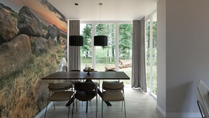 A dining area with a large table, four chairs, and two pendant lights. - Private relaxation retreat for a family (TA Gasselte)