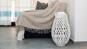 A cozy room with a bed covered in a beige blanket, a white woven lamp, and patterned pillows. - NG Collection Luna di Mare (Pittulongu)