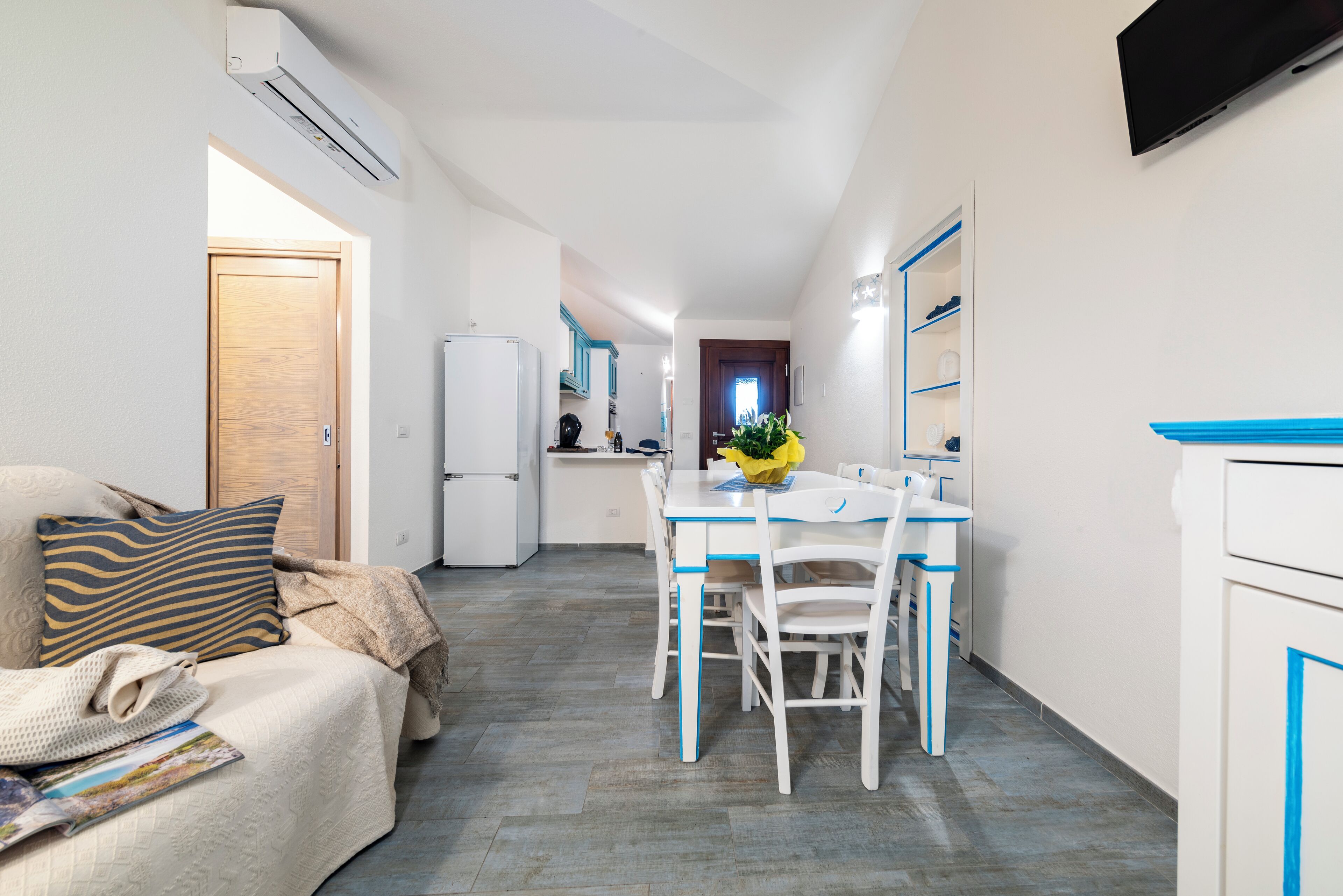 A compact living space with a kitchenette, a dining area, and a sofa with a throw blanket.