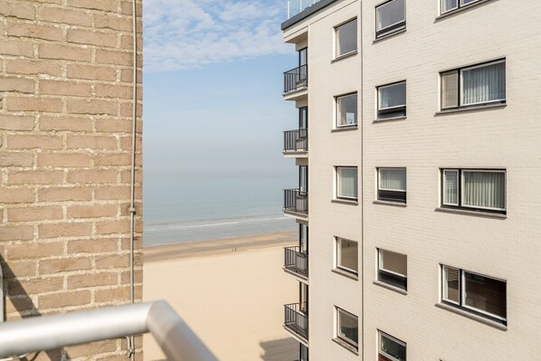 Un edificio alto con varios balcones que dan a la playa.
