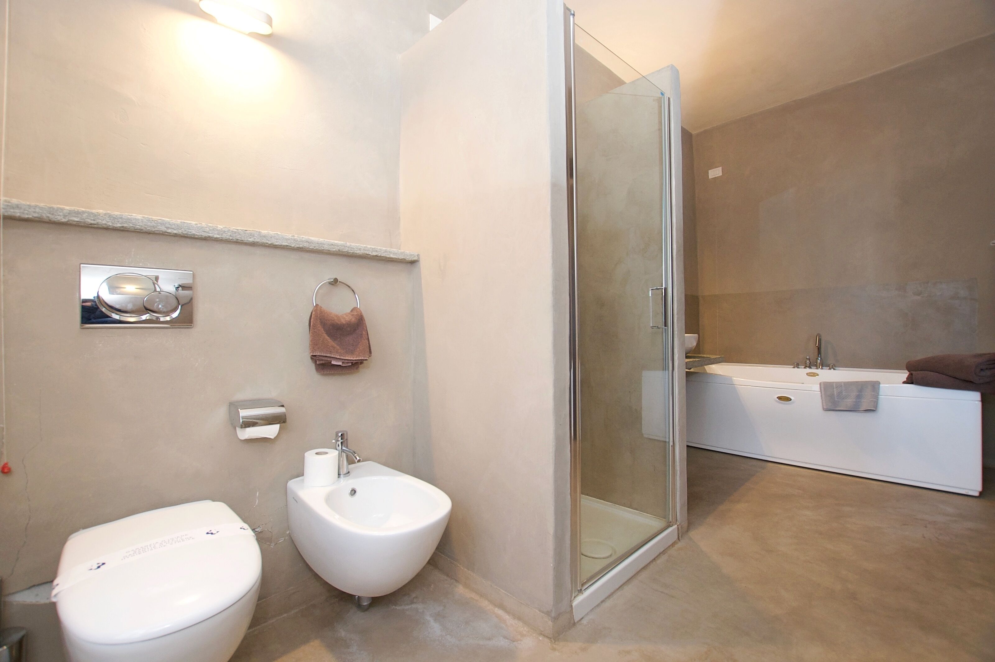 Un baño moderno con inodoro, bidé y ducha con mampara de vidrio.