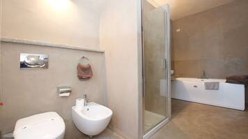 Un baño moderno con inodoro, bidé y ducha con mampara de vidrio.