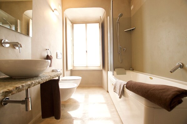 A bathroom with a large sink, a toilet, a bathtub, and a shower.