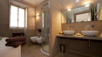 Een badkamer met een douche, twee wastafels, een toilet en een raam.