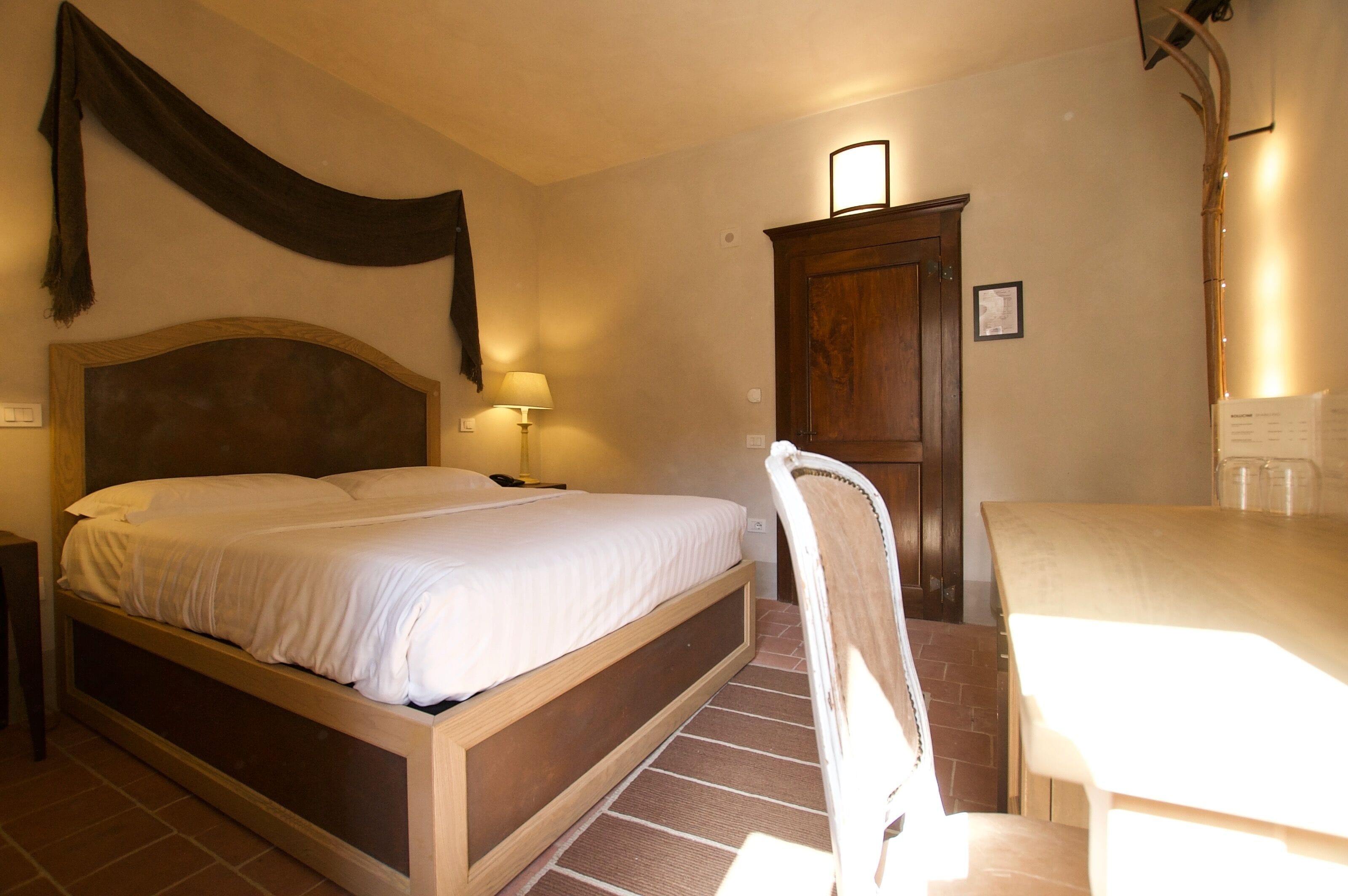 A bedroom with a wooden bed, a nightstand, a desk, and a chair.
