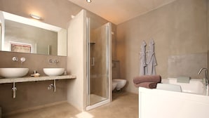 Un baño moderno con ducha envuelta en vidrio, tocador doble, bañera e inodoro.