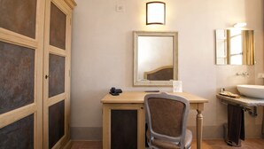 Un baño con escritorio de madera, silla, espejo y lavamanos.
