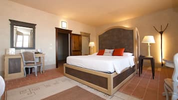 A bedroom with a large bed, a desk, a chair, a mirror, and a bedside lamp.