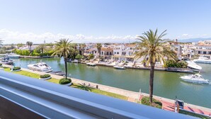 Un port de plaisance où sont amarrés des bateaux, entouré de bâtiments et de palmiers.