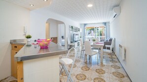 A modern kitchen with a bar area, white tiled walls, and a patterned floor. - Apartment in Empuriabrava near Sandy Beach (Empuriabrava)