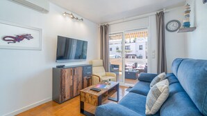 Un salon moderne avec un canapé bleu, une table basse en bois, un téléviseur et un fauteuil.