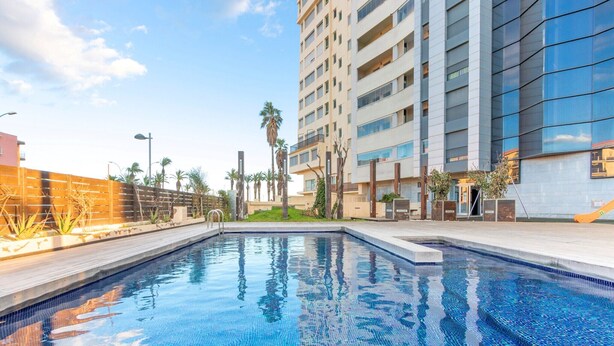 Un hôtel moderne doté d’une piscine, d’un immeuble de grande hauteur et de palmiers.