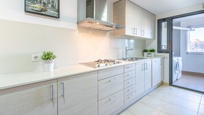 Une cuisine moderne équipée d’une cuisinière à gaz, d’une hotte en acier inoxydable et de meubles de couleur claire.
