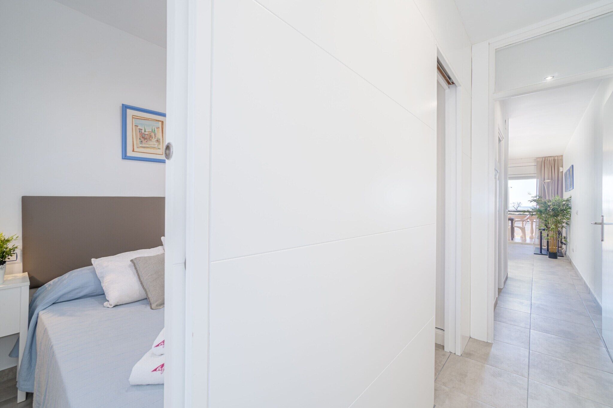 Een moderne hotelkamer met een bed, nachtkastje en een lijst met een foto aan de muur.