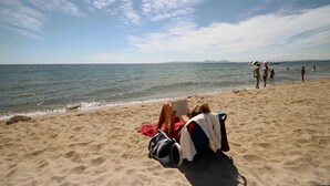 Een strand met mensen die ontspannen en lezen.