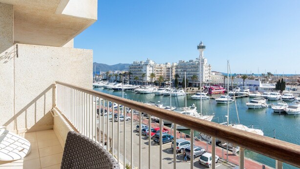 Ein Balkon mit Blick auf eine Marina, Boote und Gebäude im Hintergrund.