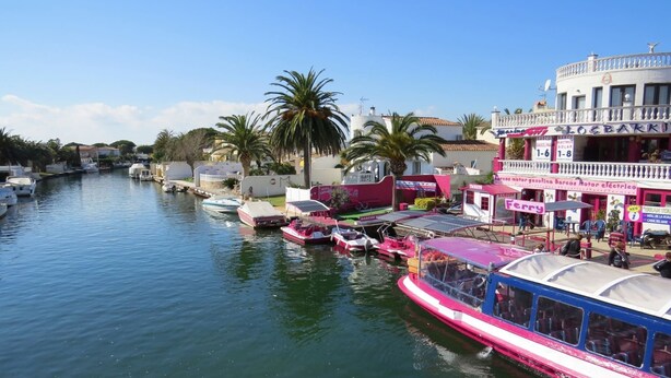 Un canal con barcos amarrados, un ferry y un edificio con un cartel que dice 'Ferry'.