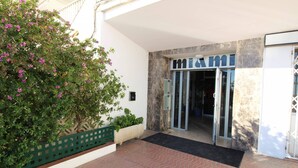 A hotel entrance with a marble facade, a green fence, and a potted plant. - Studio in Empuriabrava with Ocean Views (Empuriabrava)