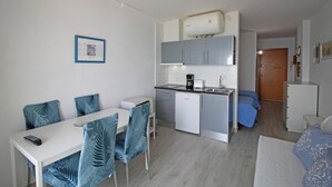 A compact hotel room with a kitchenette, a dining area with chairs, a bed, and a small bathroom. - Studio in Empuriabrava with Ocean Views (Empuriabrava)
