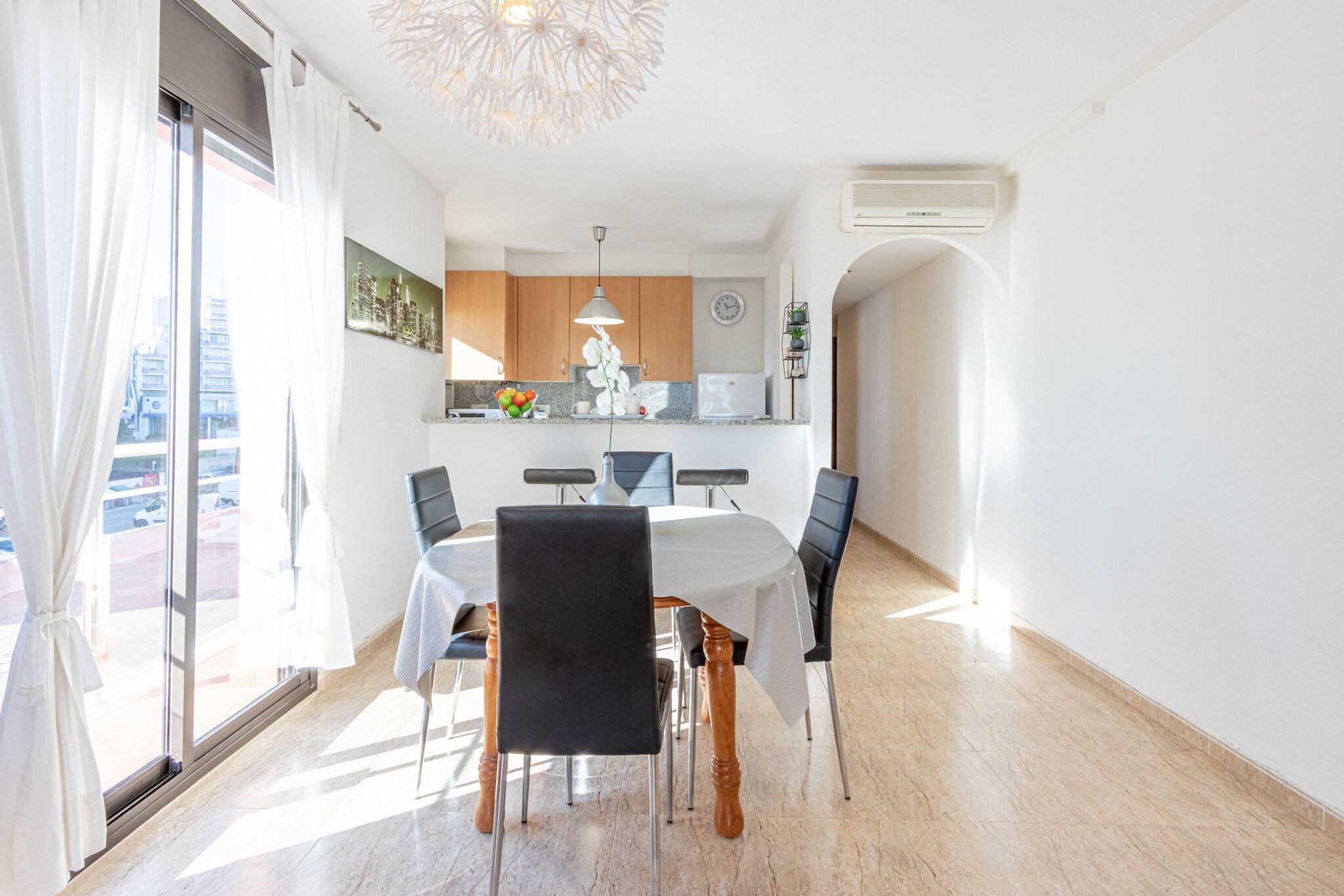 Een moderne keuken met houten kastjes, een wit aanrecht en een klok aan de muur.