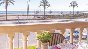 A balcony with a view of the beach, palm trees, and a parking area. - Apartment in Empuriabrava by the Beach (Empuriabrava)