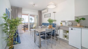 A modern kitchen with a dining area, a built-in dishwasher, and a view of the outdoors. - Apartment in Empuriabrava by the Beach (Empuriabrava)