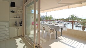 Een balkon met een tafel en stoelen, met uitzicht op een jachthaven met boten en palmbomen.