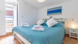 A bedroom with a bed, pillows, a painting, and a nightstand with a lamp. - Villa in Empuriabrava with Private Pool (Empuriabrava)