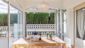 A dining area with a wooden table and chairs, a wine bottle, glasses, and a decorative bowl. - Villa in Empuriabrava with Private Pool (Empuriabrava)