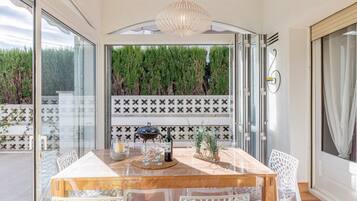Un coin repas avec une table et des chaises en bois, une bouteille de vin, des verres et un bol décoratif.
