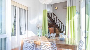 A dining area with a wooden table, white chairs, and a staircase in the background. - Villa in Empuriabrava with Private Pool (Empuriabrava)