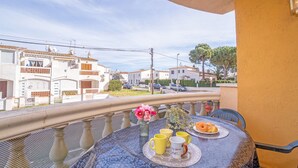 A balcony with a table set for breakfast, overlooking a residential street.