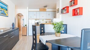 A modern kitchen with white cabinets, a dining table with chairs, and a potted plant on the table.