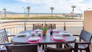 A table set for four with a view of the beach and palm trees. - Apartment in Empuriabrava by the Beach (Empuriabrava)