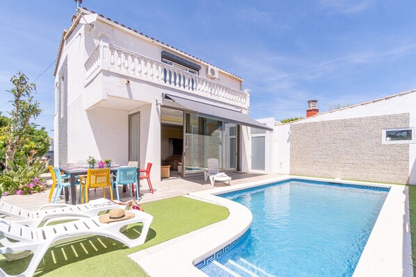 A modern house with a swimming pool, outdoor seating, and a garden. - Villa in Empuriabrava with Private Pool (Empuriabrava)