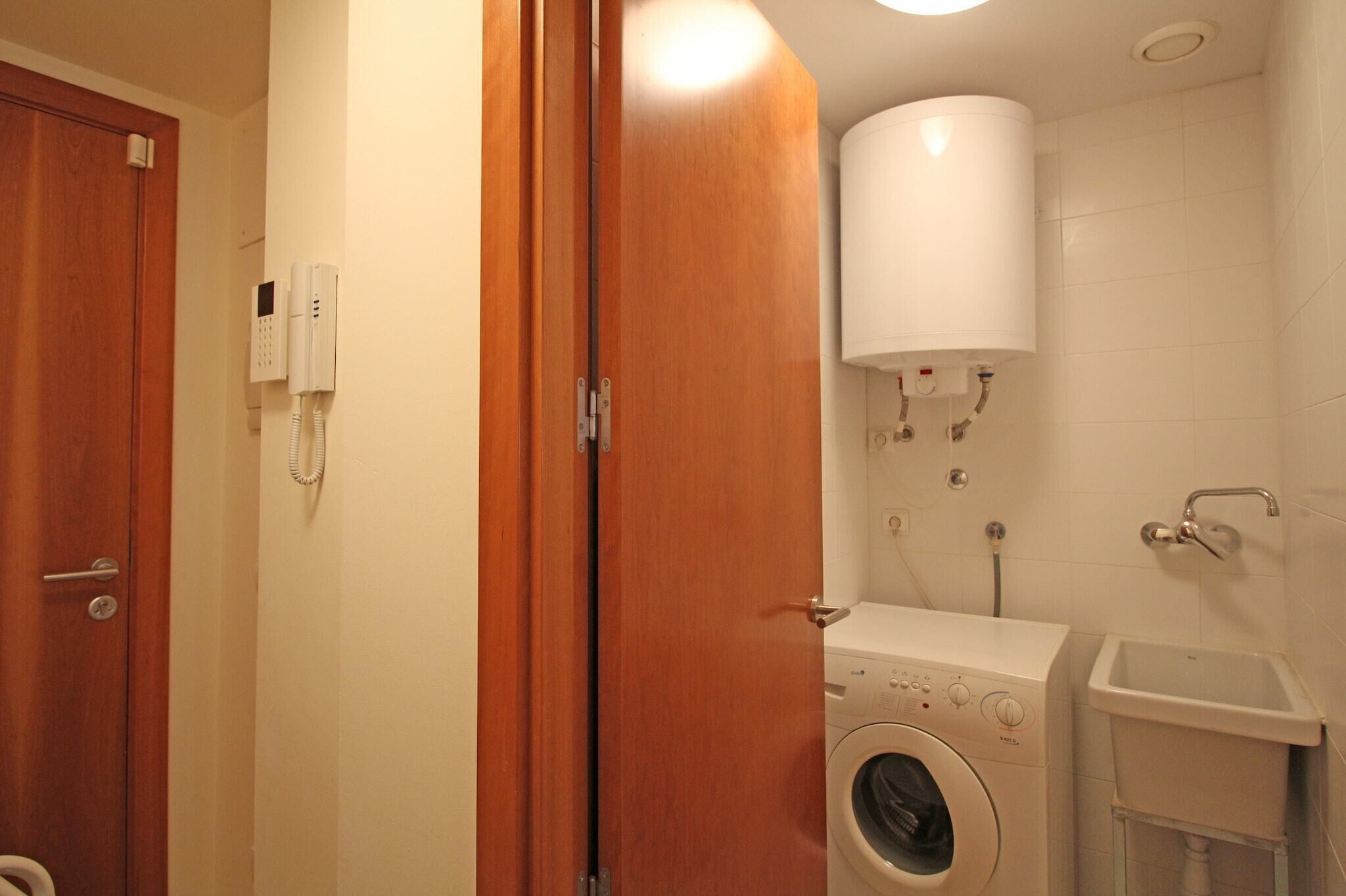 Une petite salle de bain équipée d’un lave-linge, de toilettes et d’un lavabo.