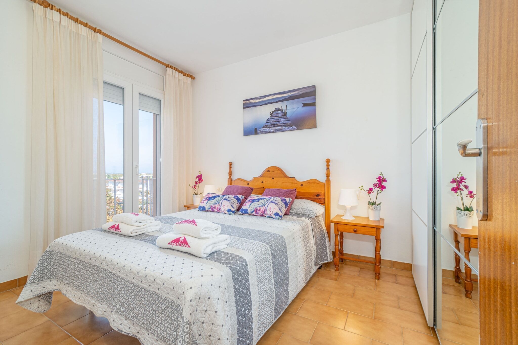 Een netjes ingerichte slaapkamer met een bed, een nachtkastje en een schilderij aan de muur.