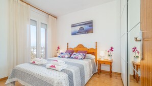 A neatly arranged bedroom with a bed, a bedside table, a nightstand, and a painting on the wall. - Apartment in Empuriabrava near Sandy Beach (Empuriabrava)