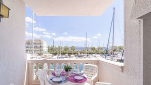 Ein Balkon mit Esstisch, mit Blick auf eine Marina und Boote.