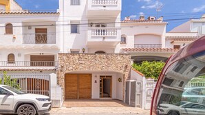 Una casa de dos plantas con fachada de piedra, puerta de garaje de madera y un balcón con barandilla de hierro forjado.