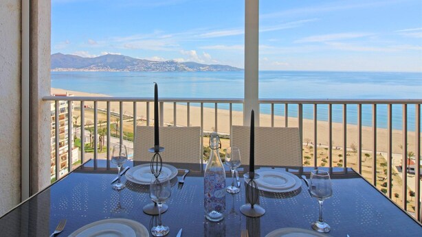A table set for dining with a view of the beach and mountains.