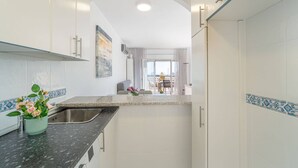 Une cuisine moderne avec des meubles blancs, un plan de travail en granit et un évier en acier inoxydable.