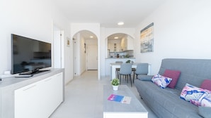 Un salon moderne avec un canapé gris, un téléviseur  à écran plat et une petite table basse.